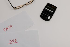Bills marked Paid and Due beside a calculator and glasses