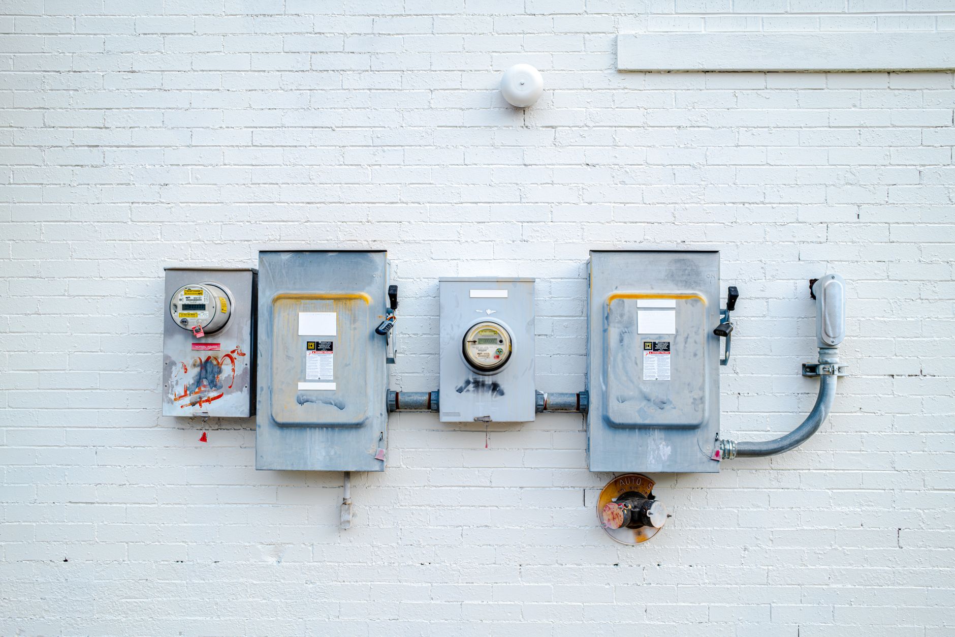 Electric meters mounted on a white brick wall