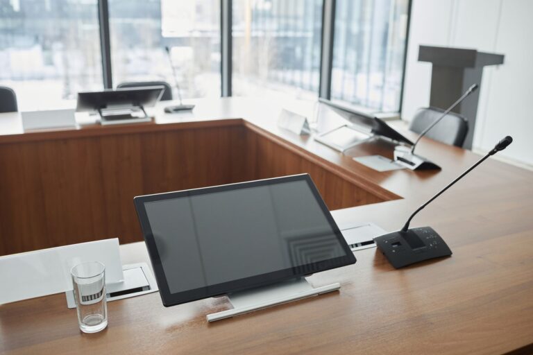 Meeting room set up with microphones and screens on a long table